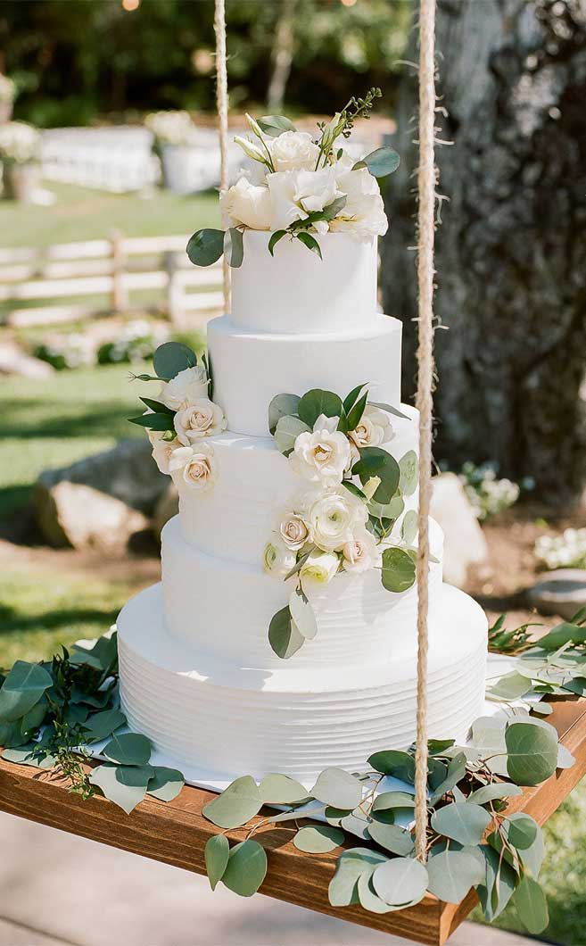 5 tier white swirl wedding cake adorned with white flowers #weddingcake #cake #wedding #weddinginspiration