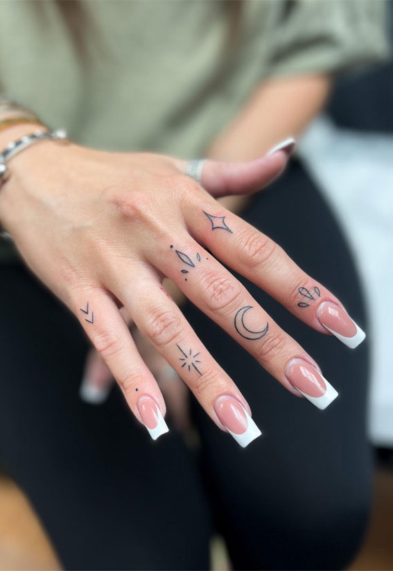 Hand poked minimalist finger tattoos.